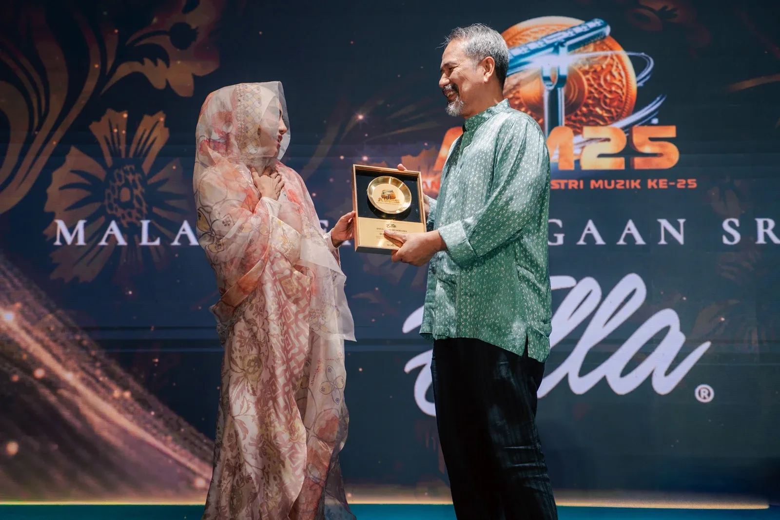 Ella menyampaikan penghargaan kepada seorang penerima pada majlis berkenaan.