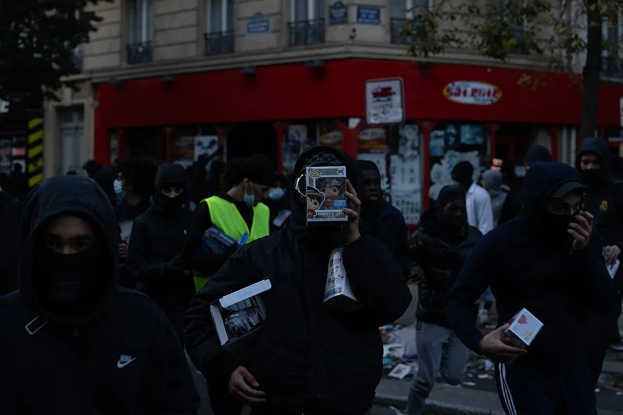 Individu bertopeng membawa barangan keluar dari kedai di Paris