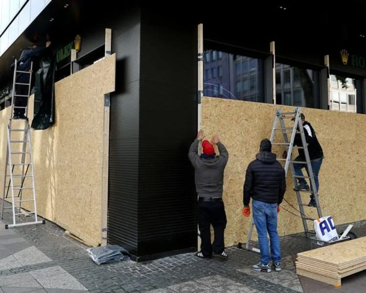 Pekerja memasang papan pelindung di kedai barang kemas di Frankfurt